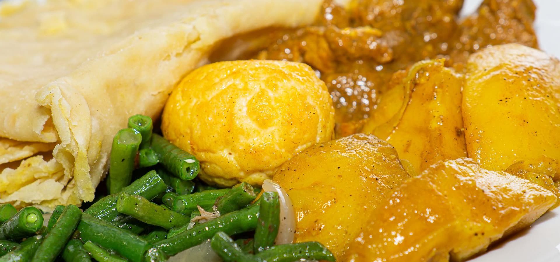 Roti met kip, aardappel, een gekookt ei en kousenband op een wit bord.